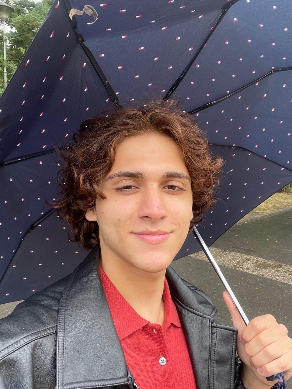 Portrait of Kanan Abdullayev smiling under an umbrella